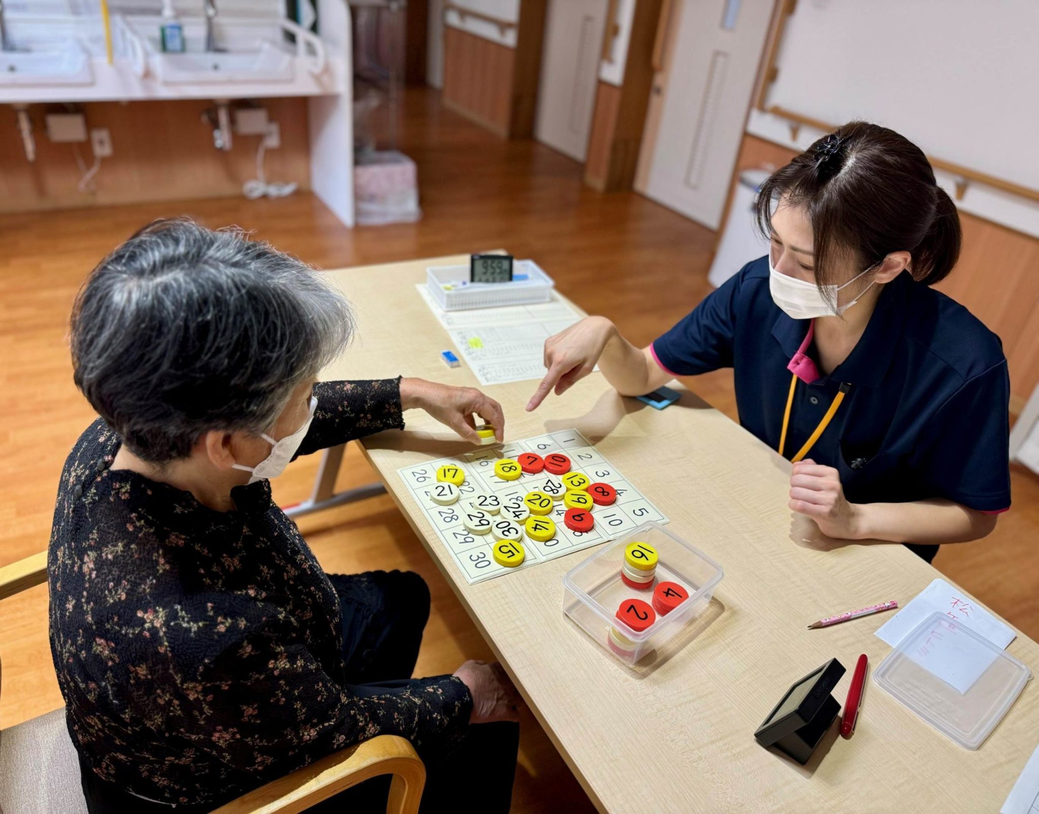 職員と入居者が数字カードを使った機能訓練を行っている様子